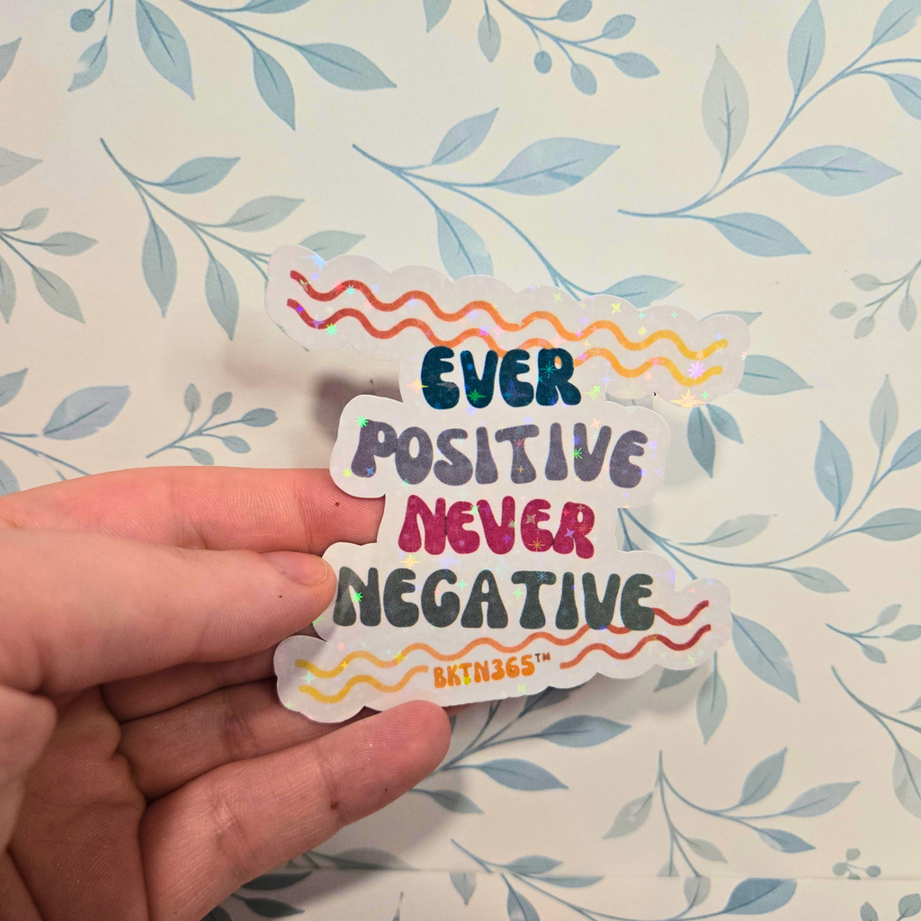 Sticker with 'Ever Positive Never Negative' text held by a hand on a leaf-patterned background