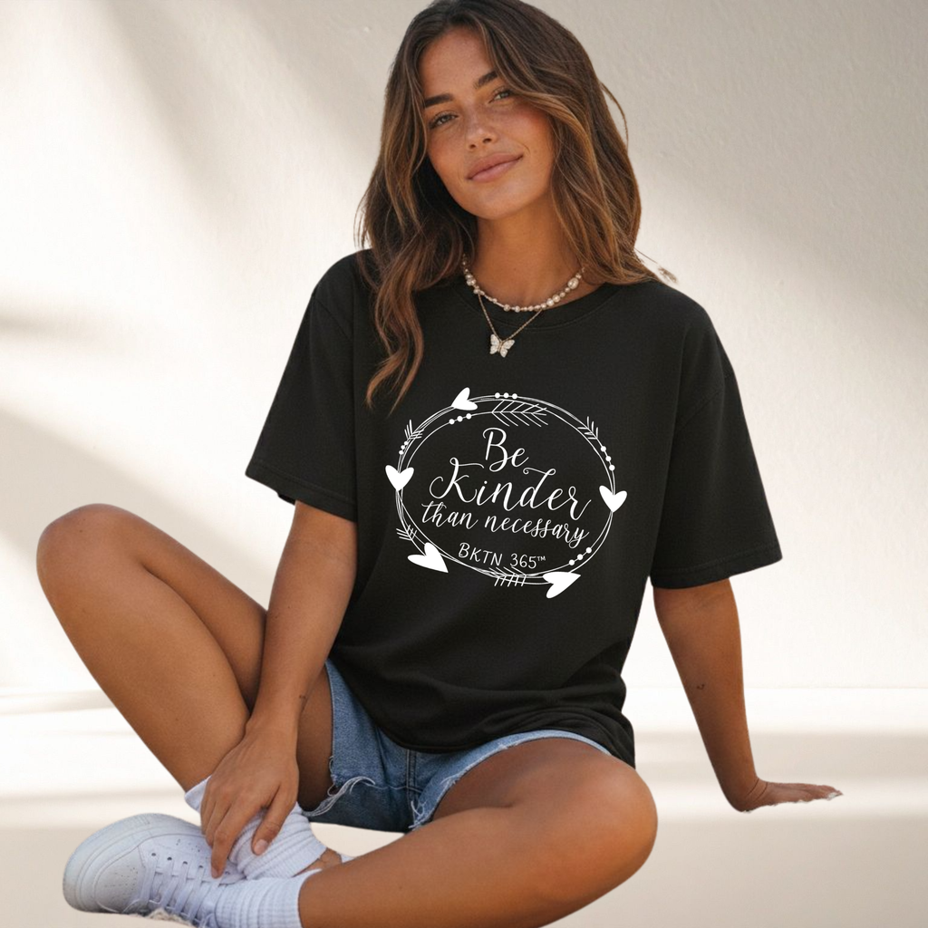 Be Kinder Than Necessary heart wreath graphic on a black unisex kindness shirt.