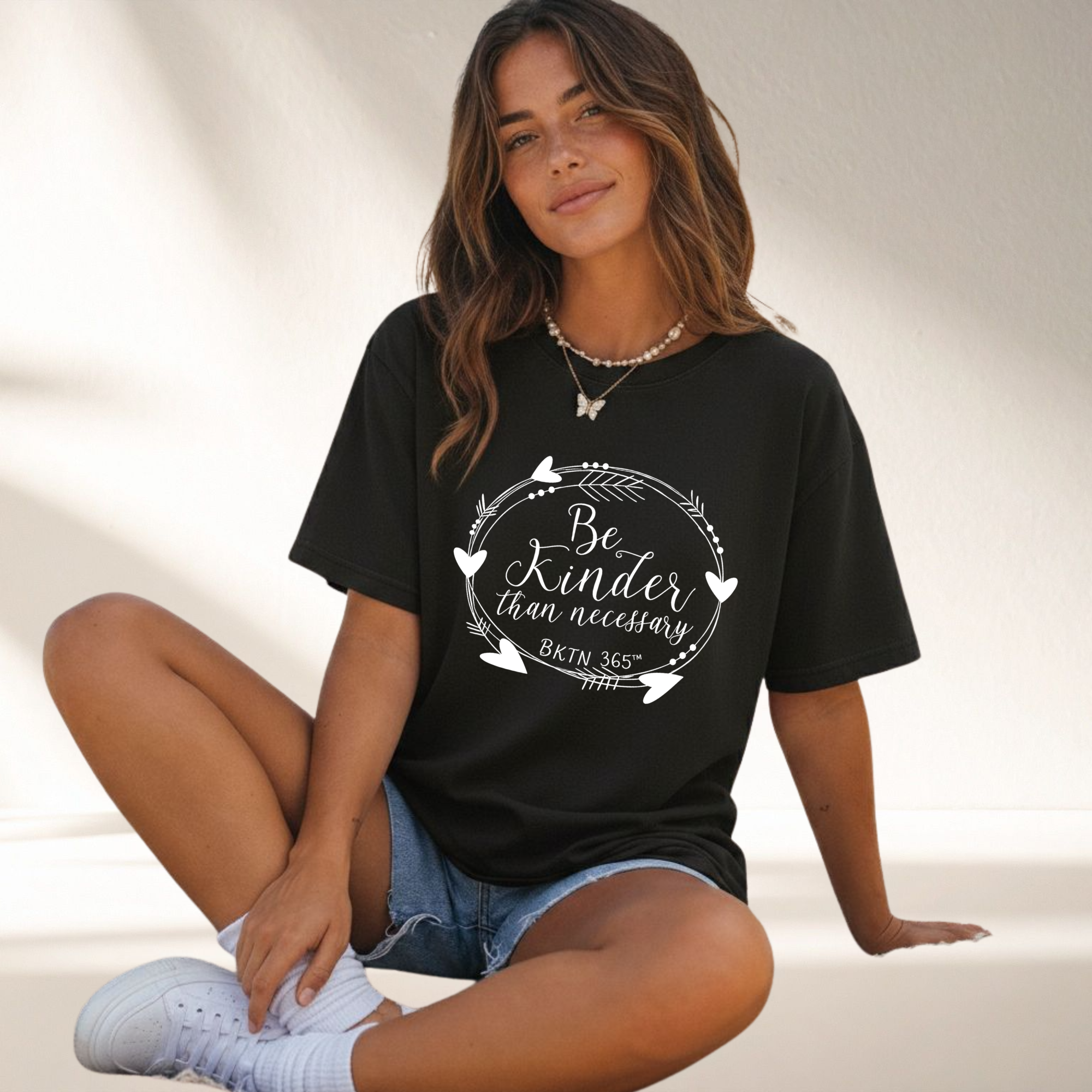 Be Kinder Than Necessary heart wreath graphic on a black unisex kindness shirt.